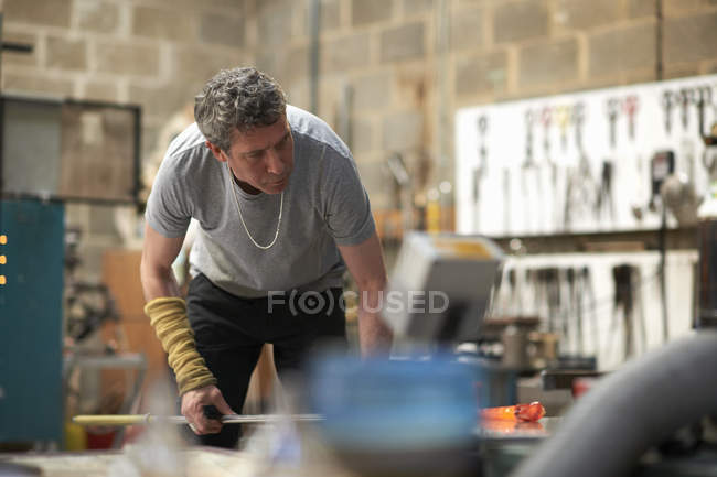 Souffleur de verre caucasien masculin en atelier à l'aide d'une pipe — Photo de stock