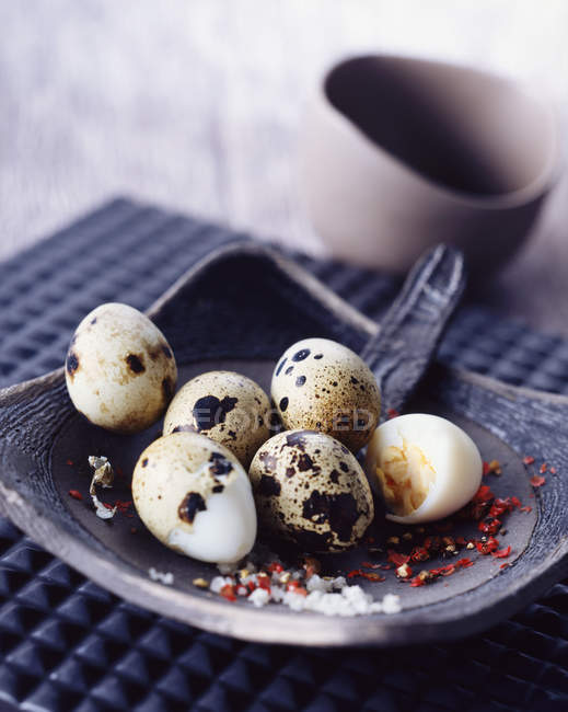 Quails eggs with salt and red peppercorns — Stock Photo