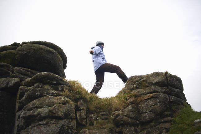 Низкоугольный вид женщины на скальную формацию, Дартмур, Девон, Великобритания — стоковое фото