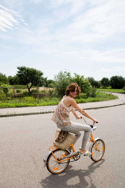Femme à vélo sur la route rurale — Photo de stock