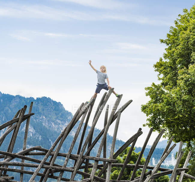 Мальчик, стоящий на вершине деревянного сооружения в детской площадке, Фуссен, Бавария, Германия — стоковое фото