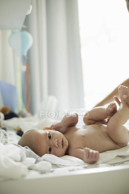 Nu bébé garçon couché sur matelas à langer coups de pied ses jambes — Photo de stock