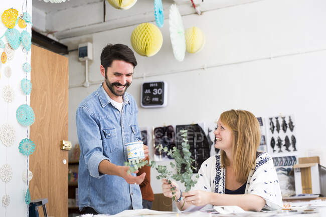 Female and male designer laughing at twig leaves in printing press studio — Stock Photo