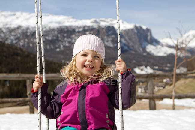 Smiling girl playing on swing outdoors — Stock Photo