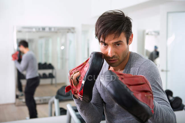 Entraîneur portant des gants rembourrés dans la salle de gym — Photo de stock