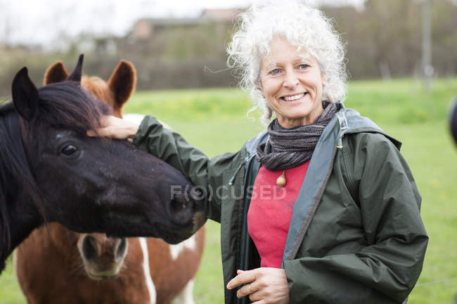 Woman stroking horse in meadow at daytime — Stock Photo
