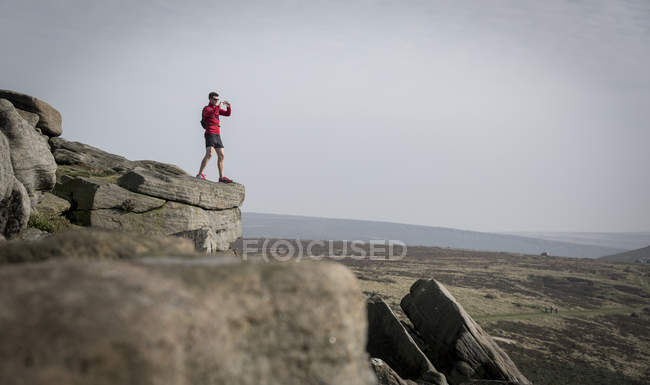 Male runner photographing from top of Stanage Edge, Peak District, Derbyshire, UK — Stock Photo