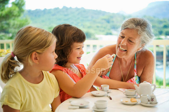 Una donna anziana e bambini che prendono il tè — Foto stock