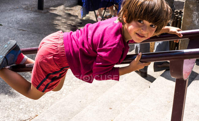 Porträt eines Jungen, der Treppengeländer hinunterrutscht — Stockfoto