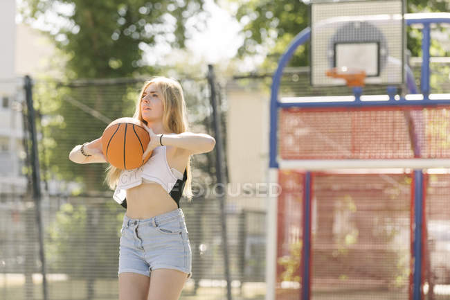Mujer joven practicando en cancha de baloncesto - foto de stock