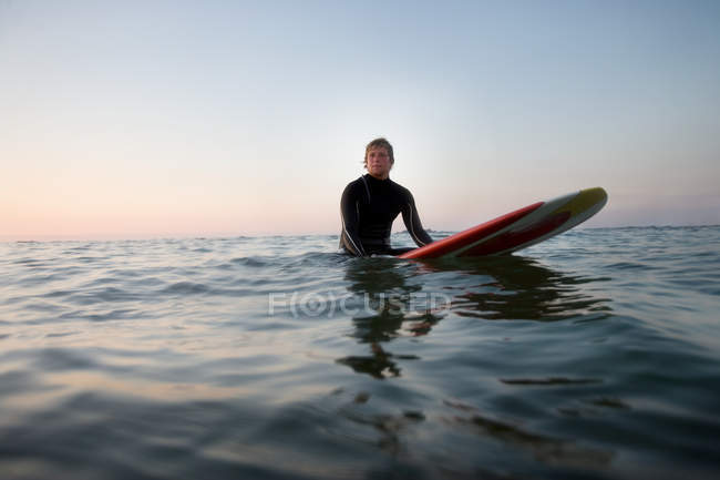 Человек сидит на доске для серфинга в воде — стоковое фото