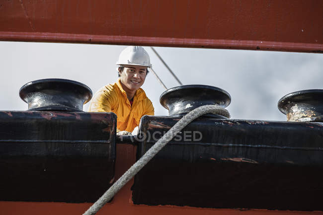 Worker fastening ropes to mooring posts on oil tanker — Stock Photo