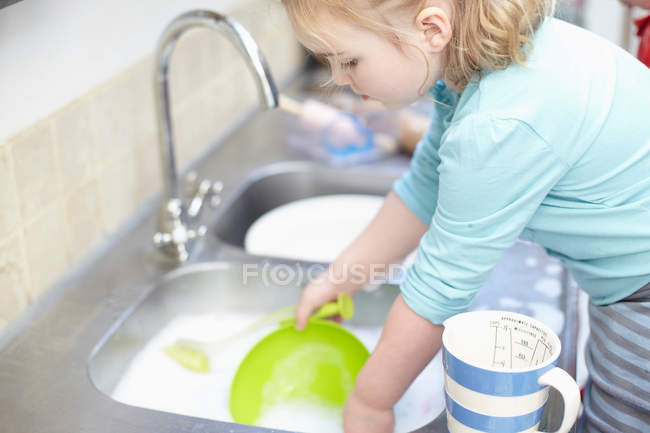 Menina lavar pratos na cozinha — Fotografia de Stock