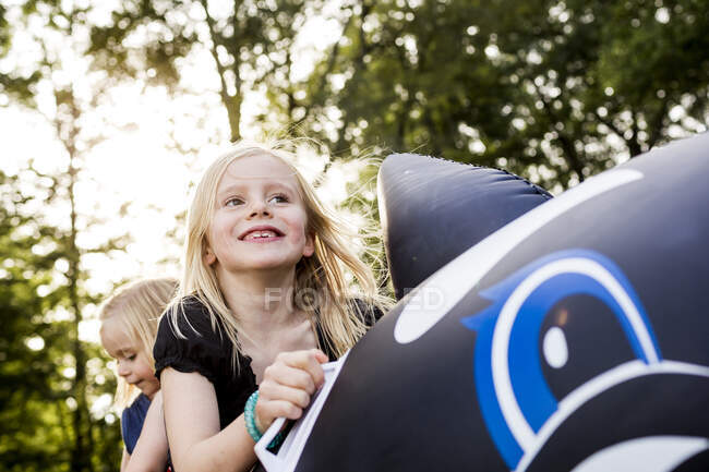 Two sisters playing on inflatable whale in park — Stock Photo
