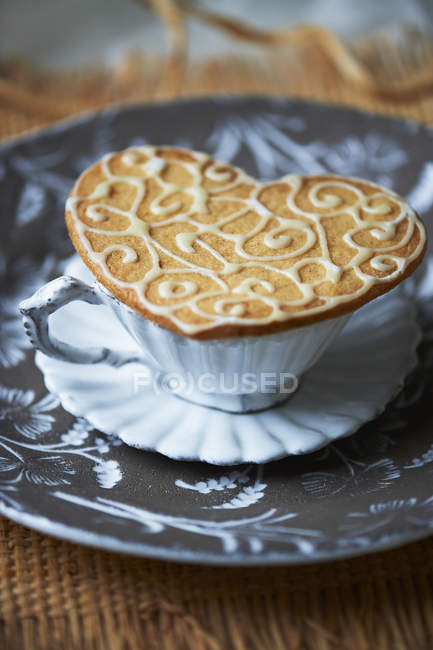 High angle view of heart shaped biscuit on top of vintage tea cup — Stock Photo