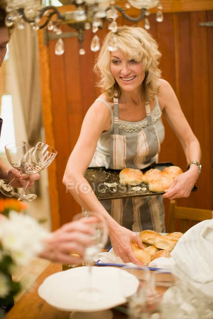 Femme plaçant des rouleaux de pain sur le plateau — Photo de stock