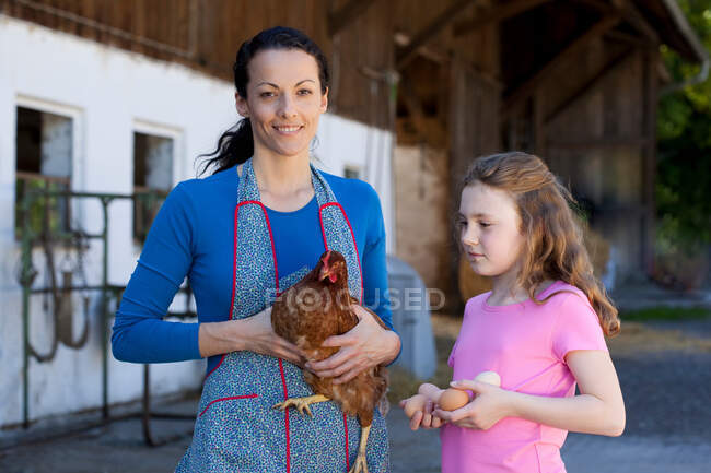 Farmwoman com galinha, filha com ovos — Fotografia de Stock