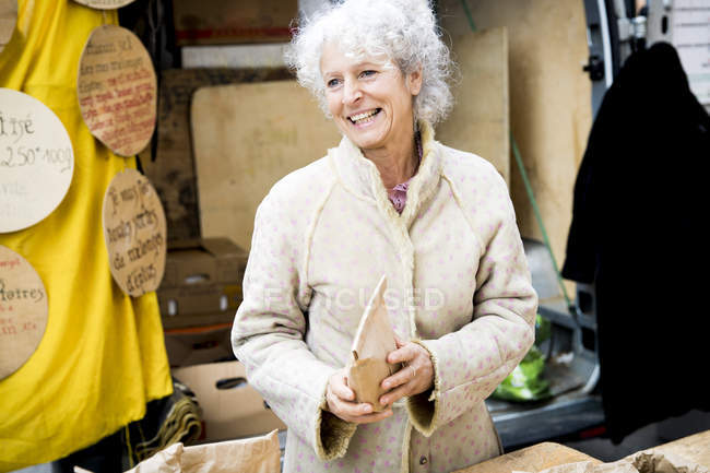 Femme mûre étable vendant des aliments séchés au marché local français — Photo de stock