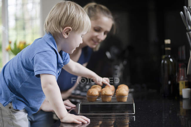 Мать и сын ждут свежеиспеченные кексы, чтобы остыть — стоковое фото