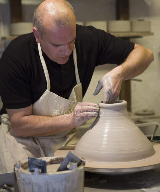 Oleiro masculino moldando panela de barro na roda de cerâmica na oficina — Fotografia de Stock