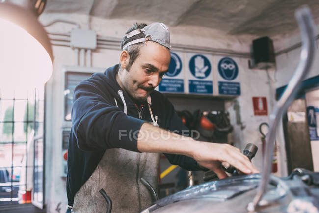 Metalworker hammering metal in forge workshop — Stock Photo