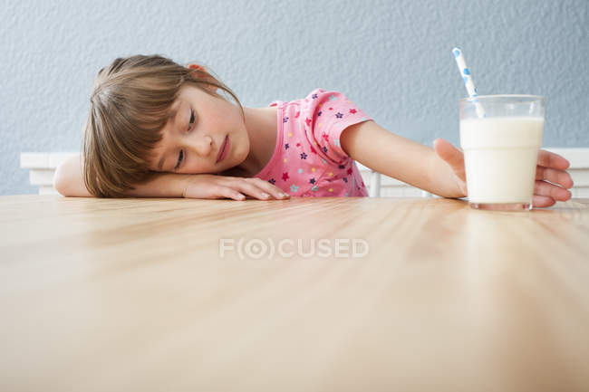Chica mirando un vaso de leche - foto de stock
