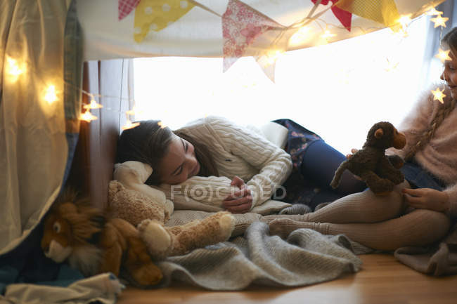 Due sorelle in camera da letto den sdraiato con giocattoli morbidi — Foto stock
