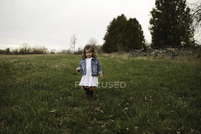 Giovane ragazza in abito bianco a piedi sul prato — Foto stock