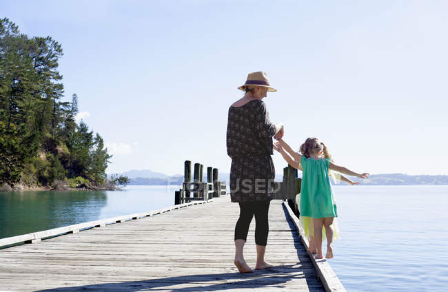 Mid adult woman and daughters playing on pier, New Zealand — Stock Photo