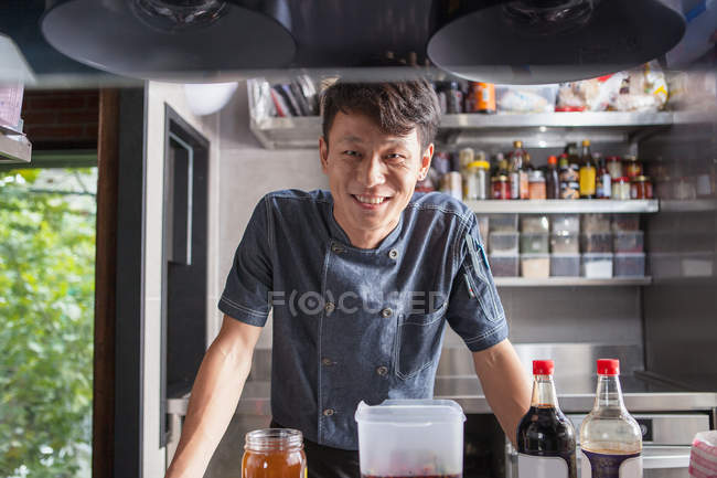 Portrait of chef in commercial kitchen looking at camera smiling — Stock Photo