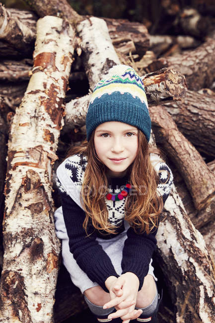 Ritratto di giovane ragazza, seduta su un mucchio di tronchi — Foto stock