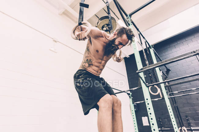 Young male cross trainer training on gymnastic rings — Stock Photo