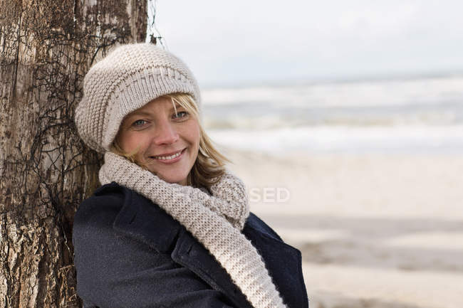 Mulher sorridente encostada ao tronco — Fotografia de Stock