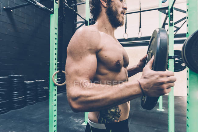 Jovem macho cross trainer preparando barbell no ginásio — Fotografia de Stock