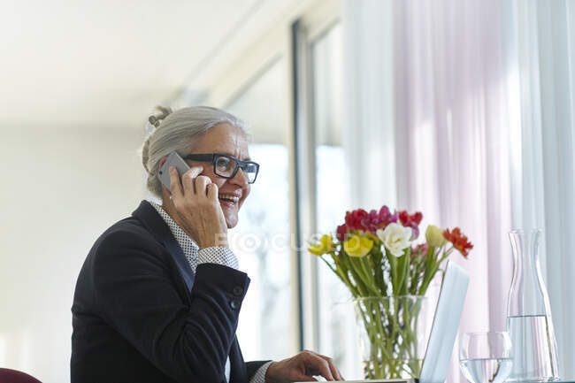 Seniorin telefoniert zu Hause mit dem Smartphone — Stockfoto