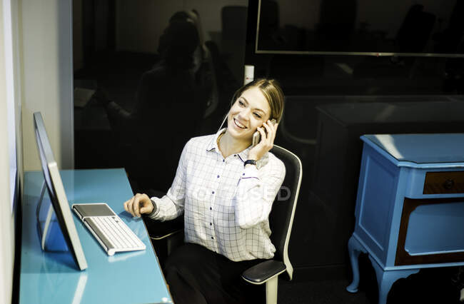 Деловая женщина разговаривает по смартфону за рабочим столом — стоковое фото