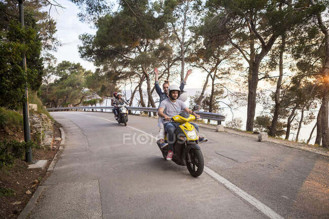 Dos parejas montando ciclomotores en carretera rural, Split, Dalmacia, Croacia - foto de stock