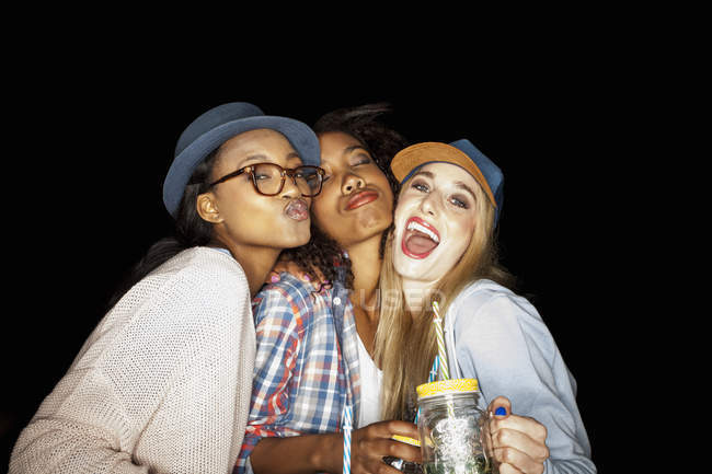 Young women huddled together holding mason jars looking at camera puckering lips — Stock Photo