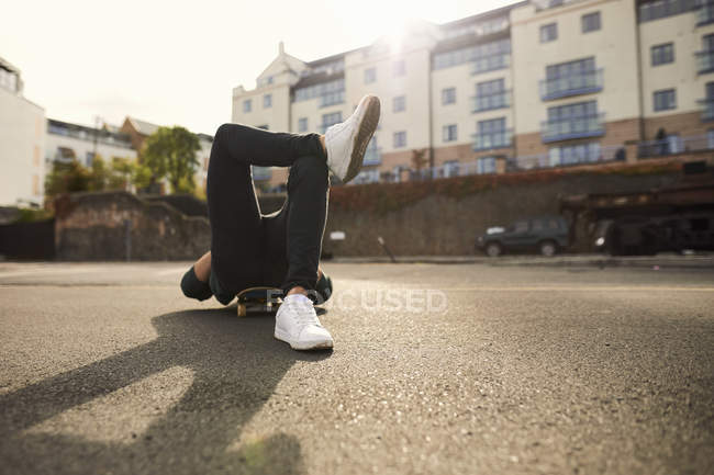 Young man laying on skateboard, relaxing, Bristol, UK — Stock Photo