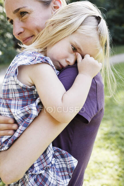 Mulher adulta média carregando filha chateada no parque — Fotografia de Stock