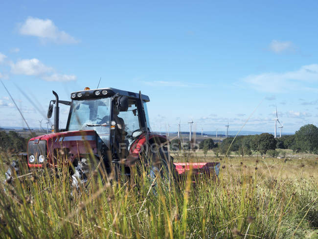 Tractor cutting grass on windfarm — Stock Photo