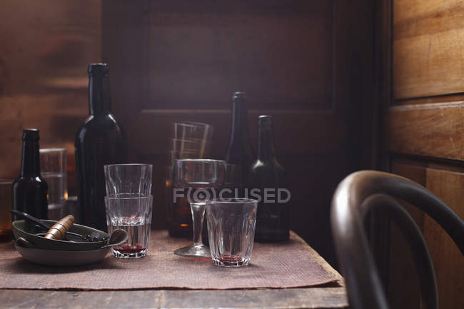 Bicchieri e bottiglie vuote sul tavolo di legno — Foto stock