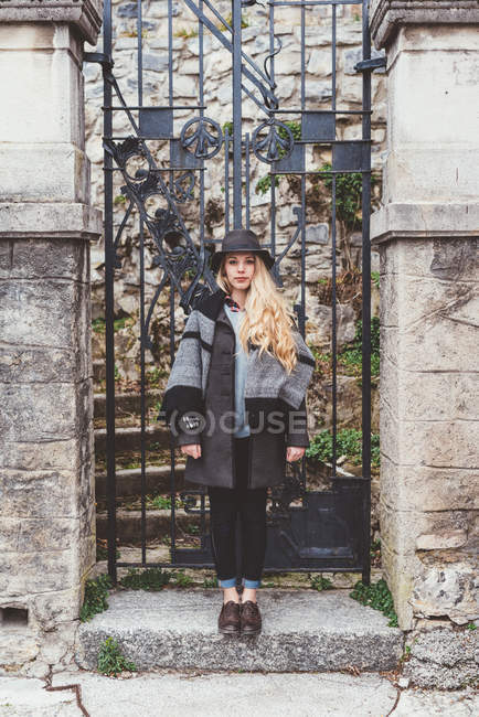 Портрет стильной молодой женщины, стоящей напротив традиционных ворот виллы, Комо, Италия — стоковое фото