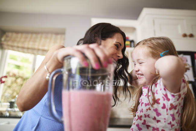 Mãe e filha fazendo smoothies no liquidificador barulhento — Fotografia de Stock