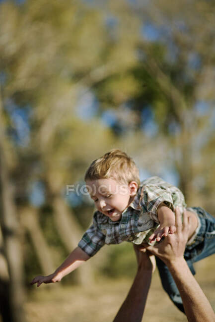 Молодого хлопчика тримають в повітрі. — стокове фото