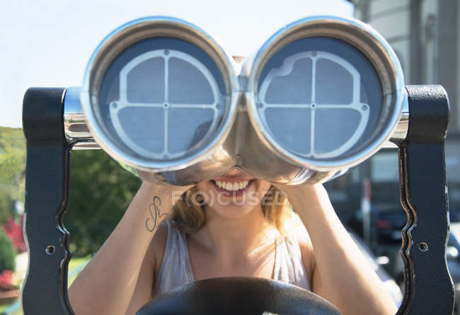 Young woman looking through coin operated binoculars at the Monte dei Cappuccini, Turin, Italy — Stock Photo