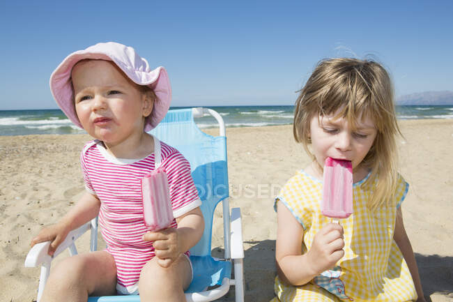 Mulher criança e irmã comendo piruetas de gelo na praia — Fotografia de Stock