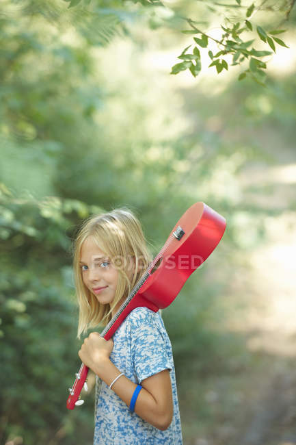 Portrait of girl with red ukulele in woodland, Buonconvento, Tuscany, Italy — Stock Photo