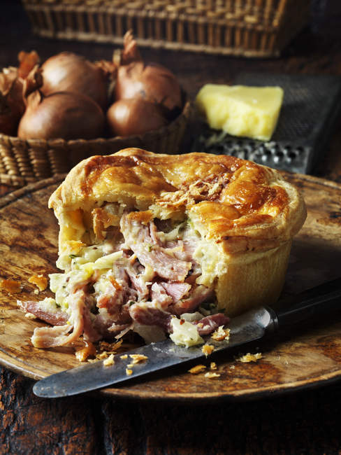 Ham, cheese and onion pie with knife on plate — Stock Photo