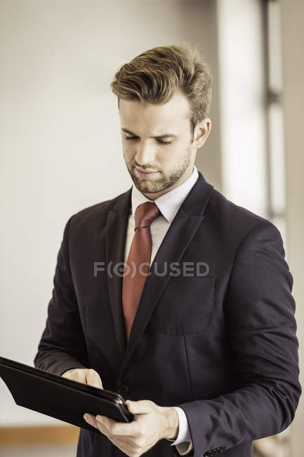 Jeune homme d'affaires utilisant écran tactile tablette numérique au bureau — Photo de stock
